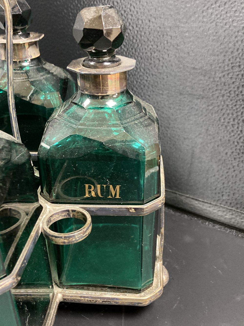 A set of four Victorian cut green glass spirit bottles, in a plated frame, 28cm,